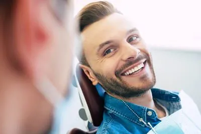 man smiling at his dental checkup after having a tooth extracted
